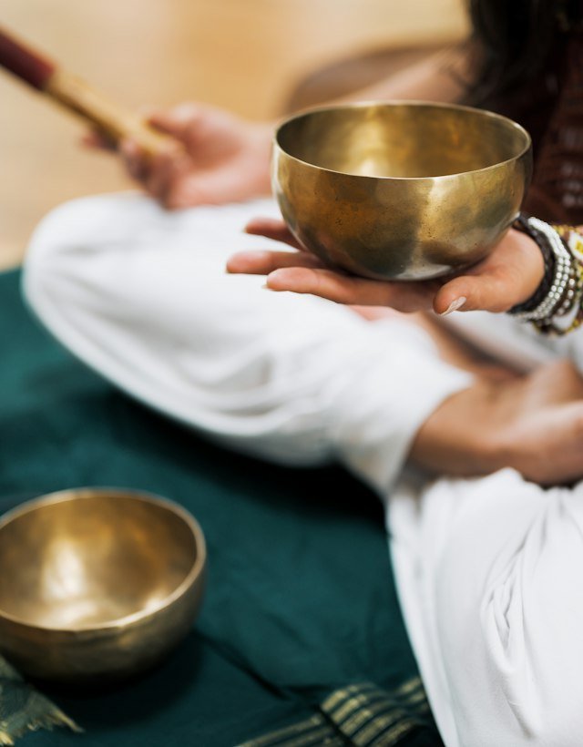 Hands holding a brass singing bowl on a green cloth