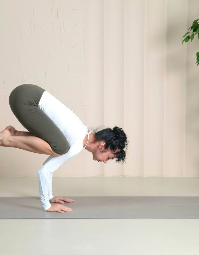A woman balancing in crow pose on a mat