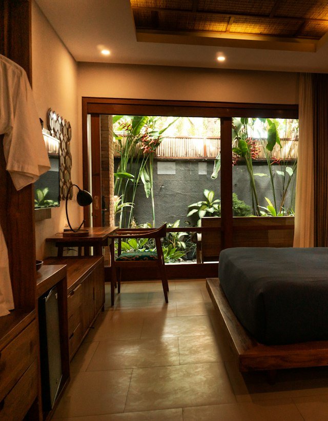 A calm bedroom with a wooden bed and a view of a private garden